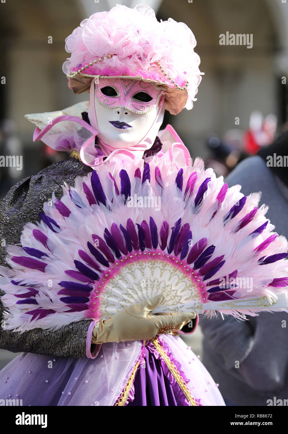 Venice, VE, Italy - February 5, 2018: Woman with handheld fan and white mask during carnival Stock Photo