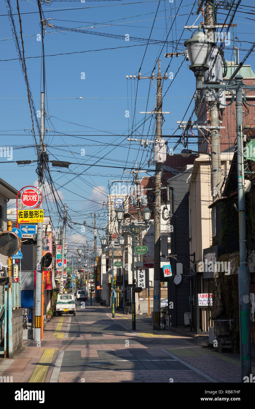Beppu, Japan - November 3, 2018: Small street in the centre of the city of Beppu with signs and lots of electricity wires Stock Photo