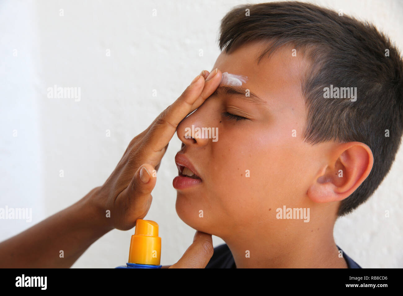 Mother putting sun protection cream on her son's face in Salento, Italy. Stock Photo