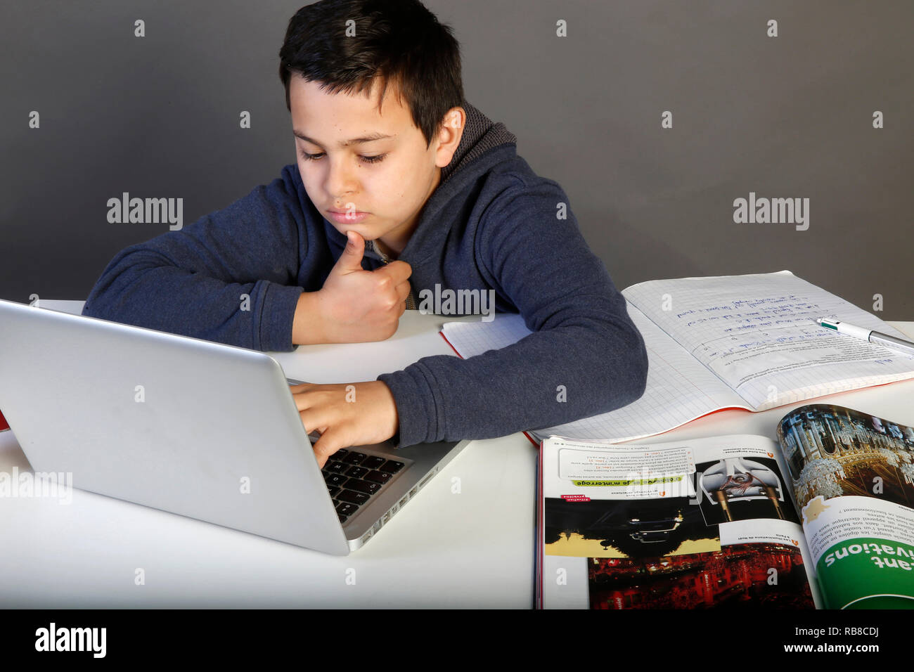 12-year-old schoolboy doing his homework with a laptop. Paris, France. Stock Photo