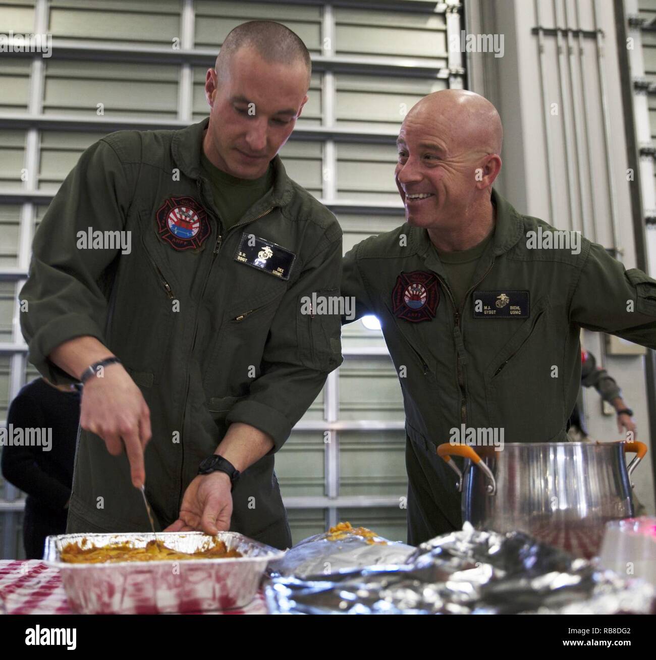 U.S. Marine Corps Staff Sgt. Sean Dee, left, the Aircraft Rescue and Firefighting station captain, and Gunnery Sgt. Matthew Viehl, assistant chief of operations at ARFF, prepare to serve food for the ARFF Tsuta Orphanage Christmas party at Marine Corps Air Station Iwakuni, Japan, Dec. 10, 2016. ARFF holds the party annually to help spread Christmas cheer to the orphans and to bring service members, their families and the Japanese together. Marines volunteered their time and provided the children with a homemade, American meal. Stock Photo