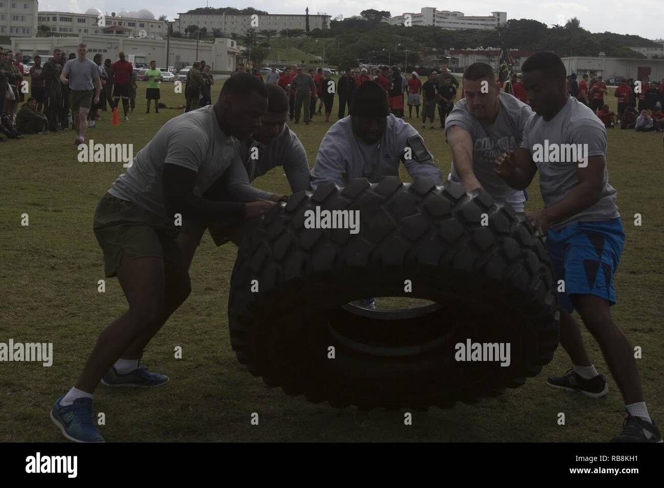 Sgt. Major Jeffrey A. Young, center, works with Headquarters and Support Battalion Marines to complete the tire flip competition Dec. 16 during the Camp Commander’s Jingle Bell Challenge aboard Camp Foster, Okinawa Japan. The tire flip was one of six challenges included in the Camp Commander’s Jingle Bell Challenge. Young is the sergeant major of Headquarters and Support Battalion, Marine Cops Installations Pacific-Marine Corps Base Camp Butler, Japan. Stock Photo