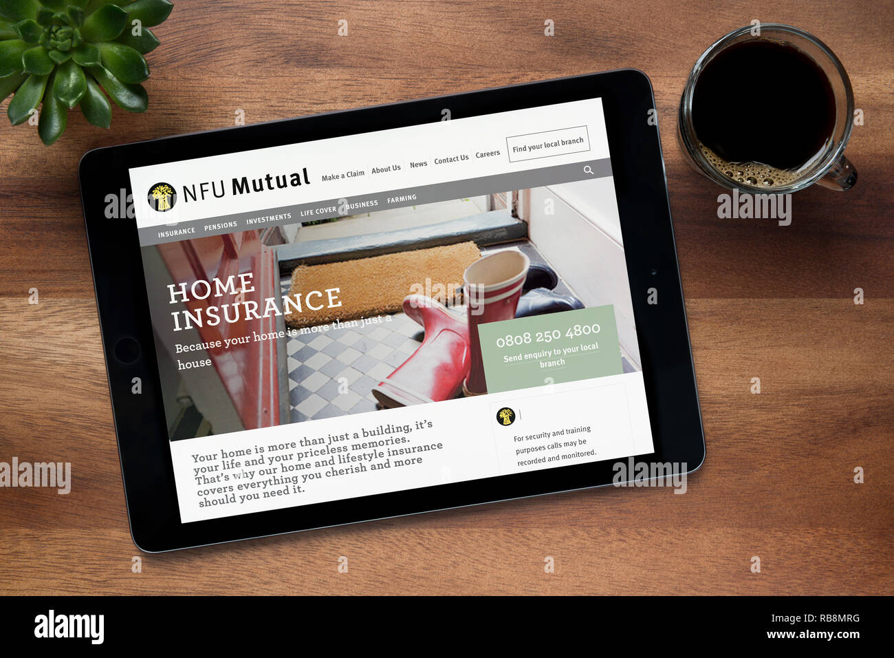The website of NFU Mutual is seen on an iPad tablet, on a wooden table along with an espresso coffee and a house plant (Editorial use only). Stock Photo