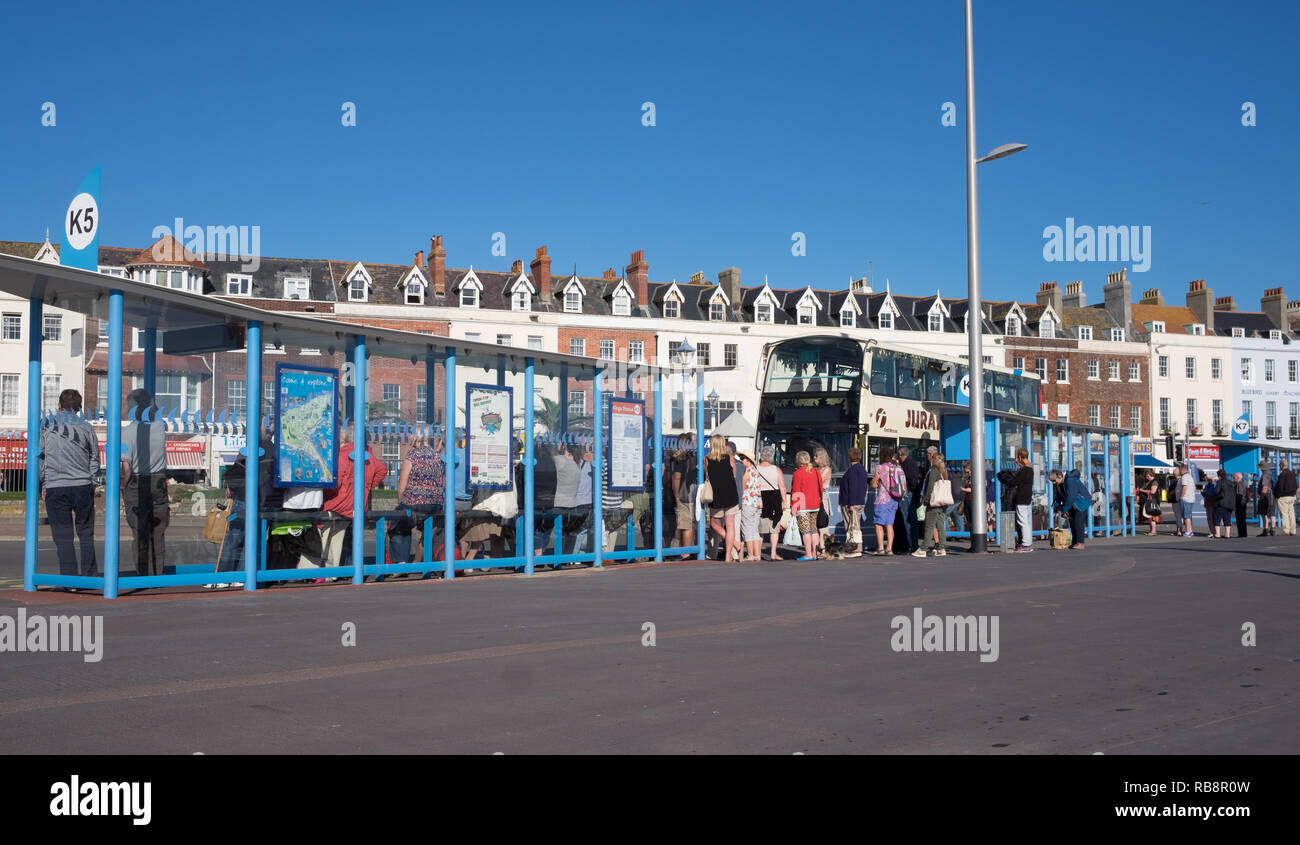 People, queuing for a bus on the Esplanade at weymouth Stock Photo