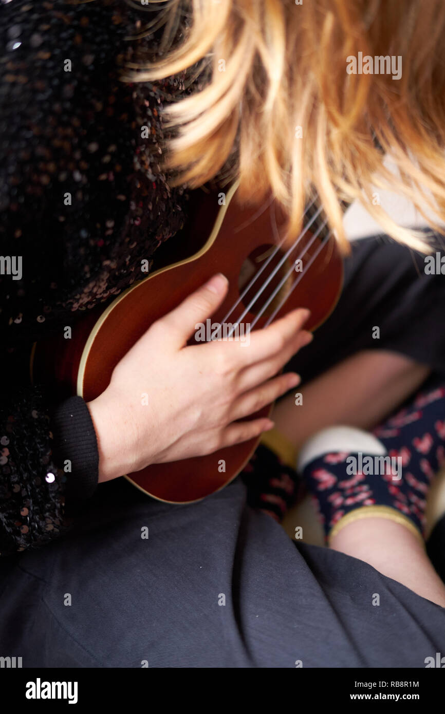 Close up of a girl playing a ukulele stringed instrument Stock Photo
