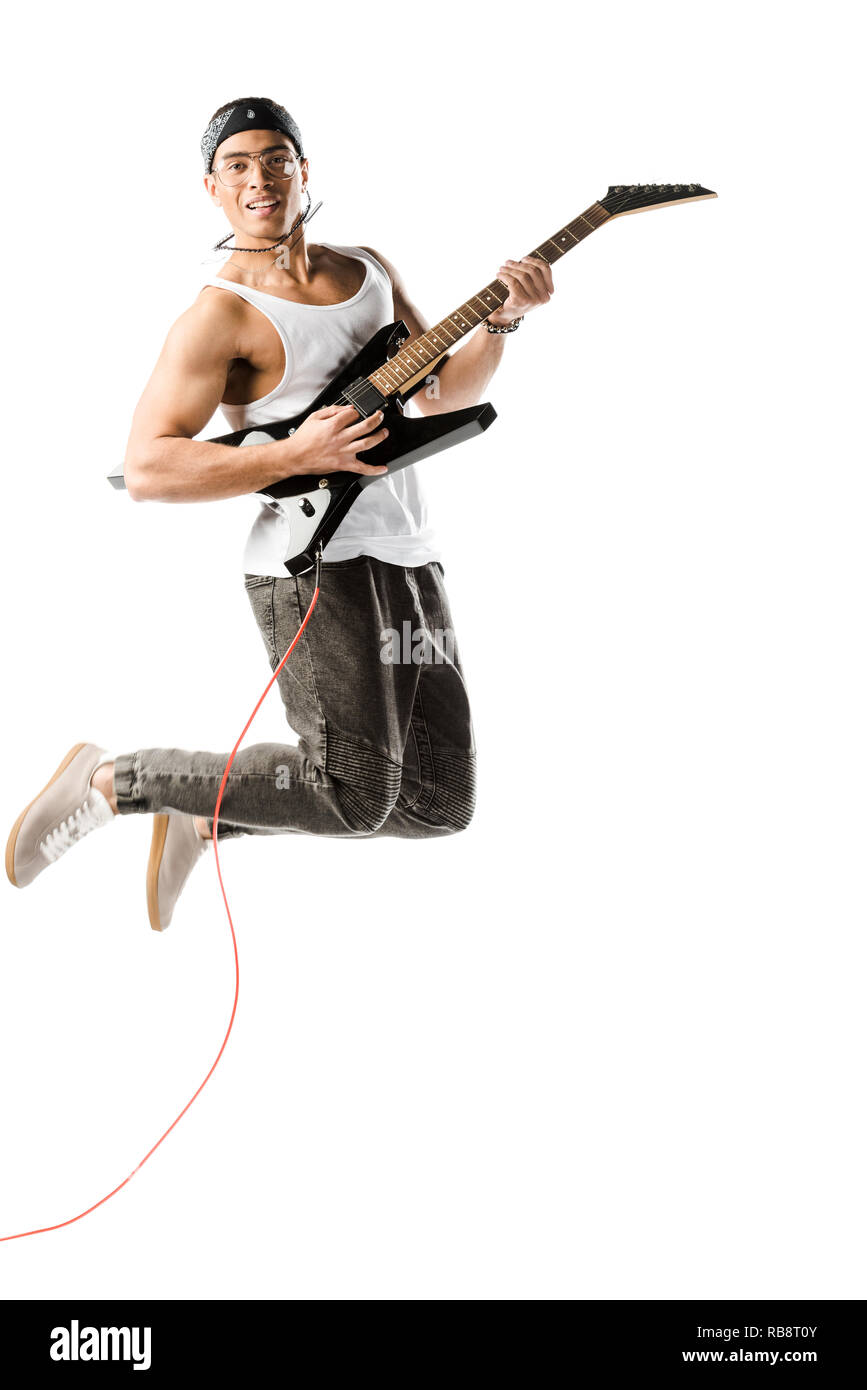 happy young male rocker jumping and playing on electric guitar isolated ...