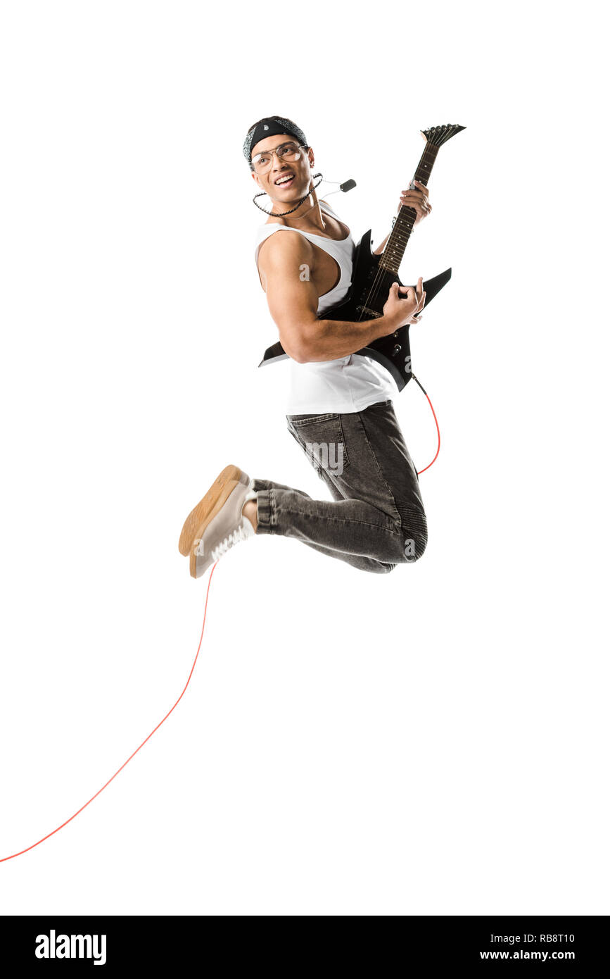 cheerful young man jumping and playing on electric guitar isolated on white Stock Photo