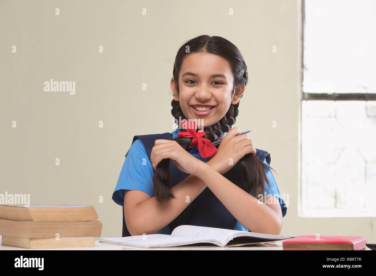 Rural girl in school uniform playing with her hair while studying Stock Photo