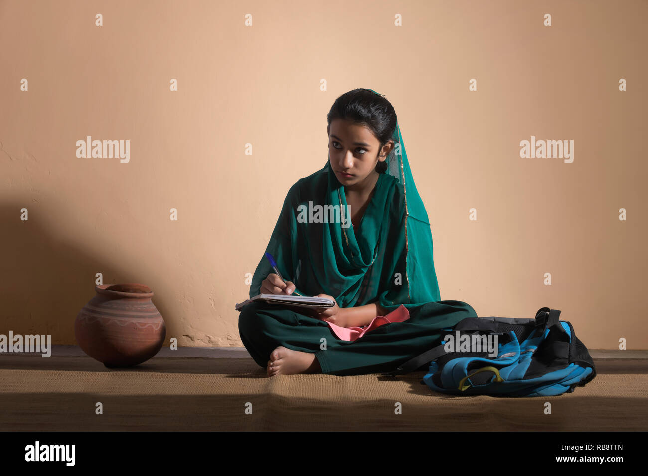 Rural girl in traditional clothing sitting on floor and studying Stock Photo