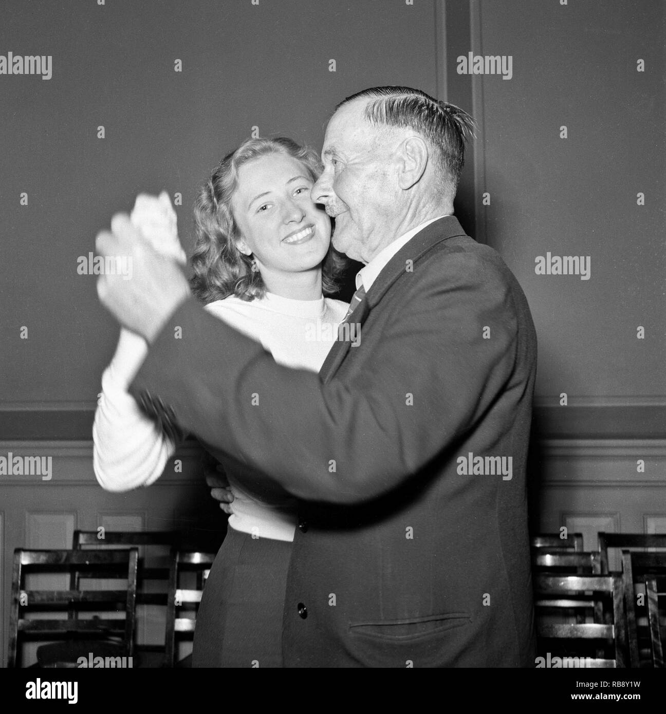 Dancing in the 1940s. A young woman and an elderly man dancing together 1942. He is probably Swedens most sung about man as the Swedish songwriter Evert Taube wrote a song named after him, Calle Schewen. Stock Photo