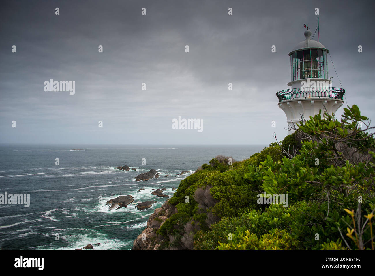 Sugarloaf Point lighthouse at Seal Rocks, Myall Lakes National Park, NSW, Australia. Lighthouse on hilltop, rough seas and grey cloud sky Stock Photo