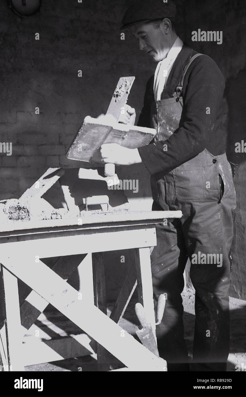 1950, historical, post-war Britain and with the pits closing, a former Welsh miner with a plaster trowel and hawk as he practices the new skill of plastering, Merthyr, Wales. Stock Photo
