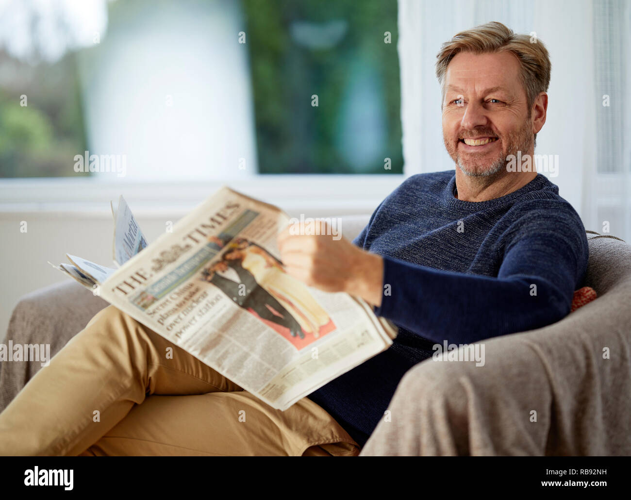 Man relaxing on a sofa reading a paper Stock Photo