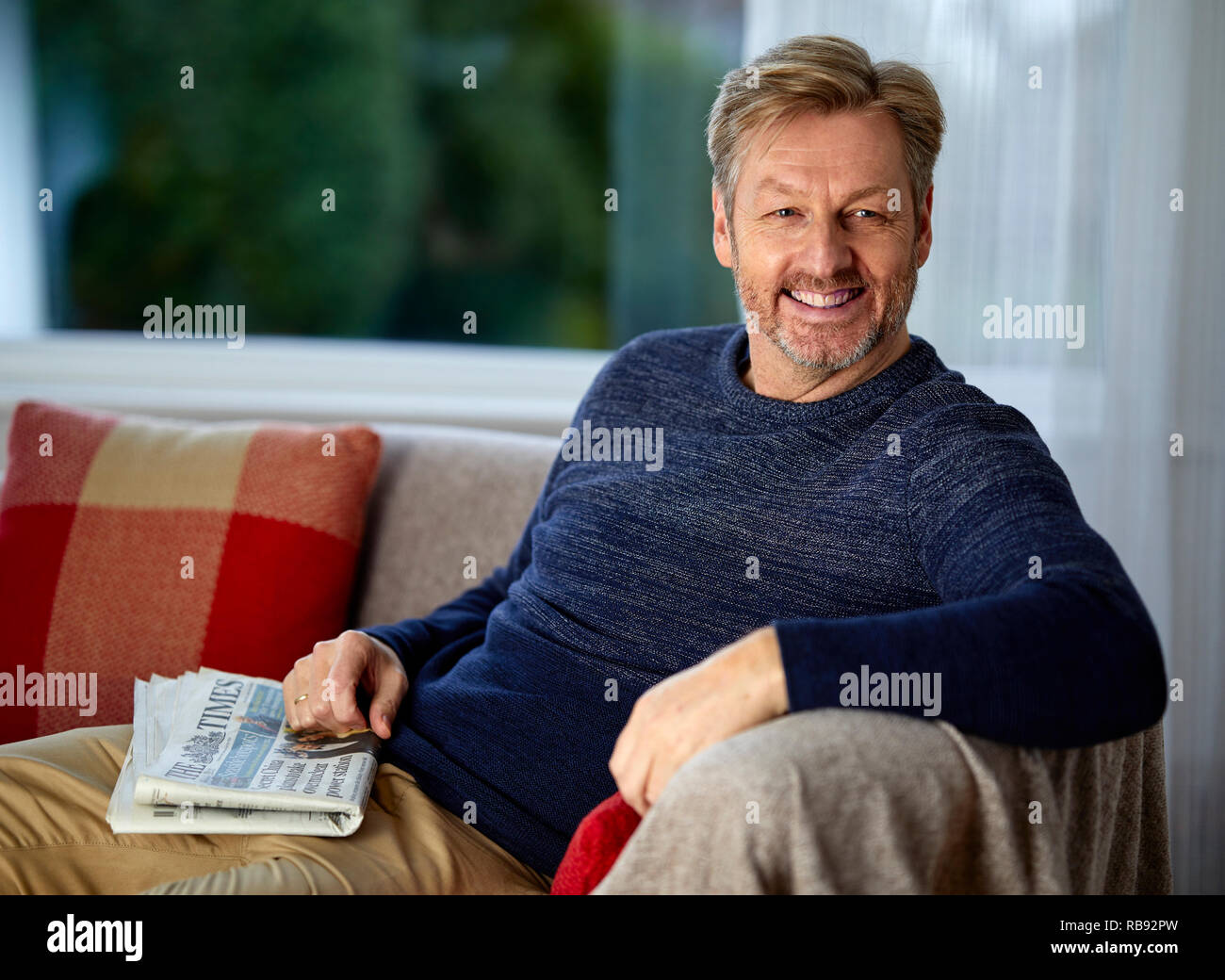 Man sat relaxing on a sofa Stock Photo