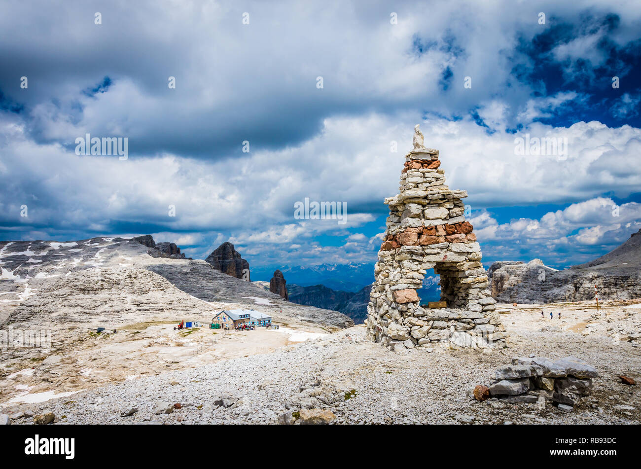 Sella massif, Dolomites mountains, Italian Alps. Cairn on the stone in the foreground and rifugio Boe in the second plane. Hiking to Piz Boe Stock Photo