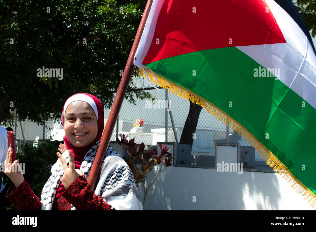 A nice photo of a traditional Palestinian woman marching with the national flag Stock Photo