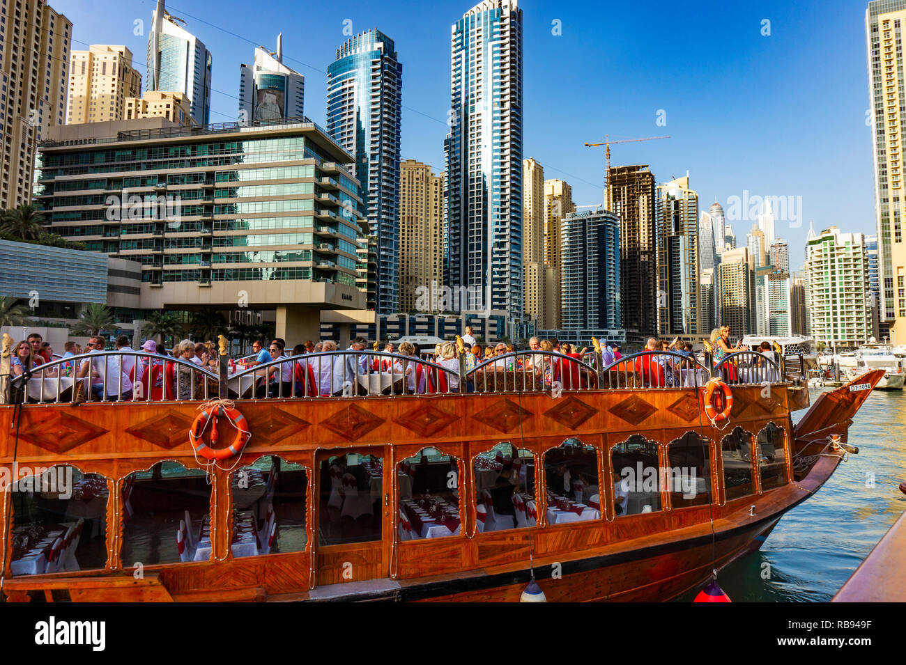 Dubai, UAE 11. 10. 2018 : Famous traditional wooden old dhow cruise tour in the marina with tourist on the board and modern skyscrapers in the backgou Stock Photo
