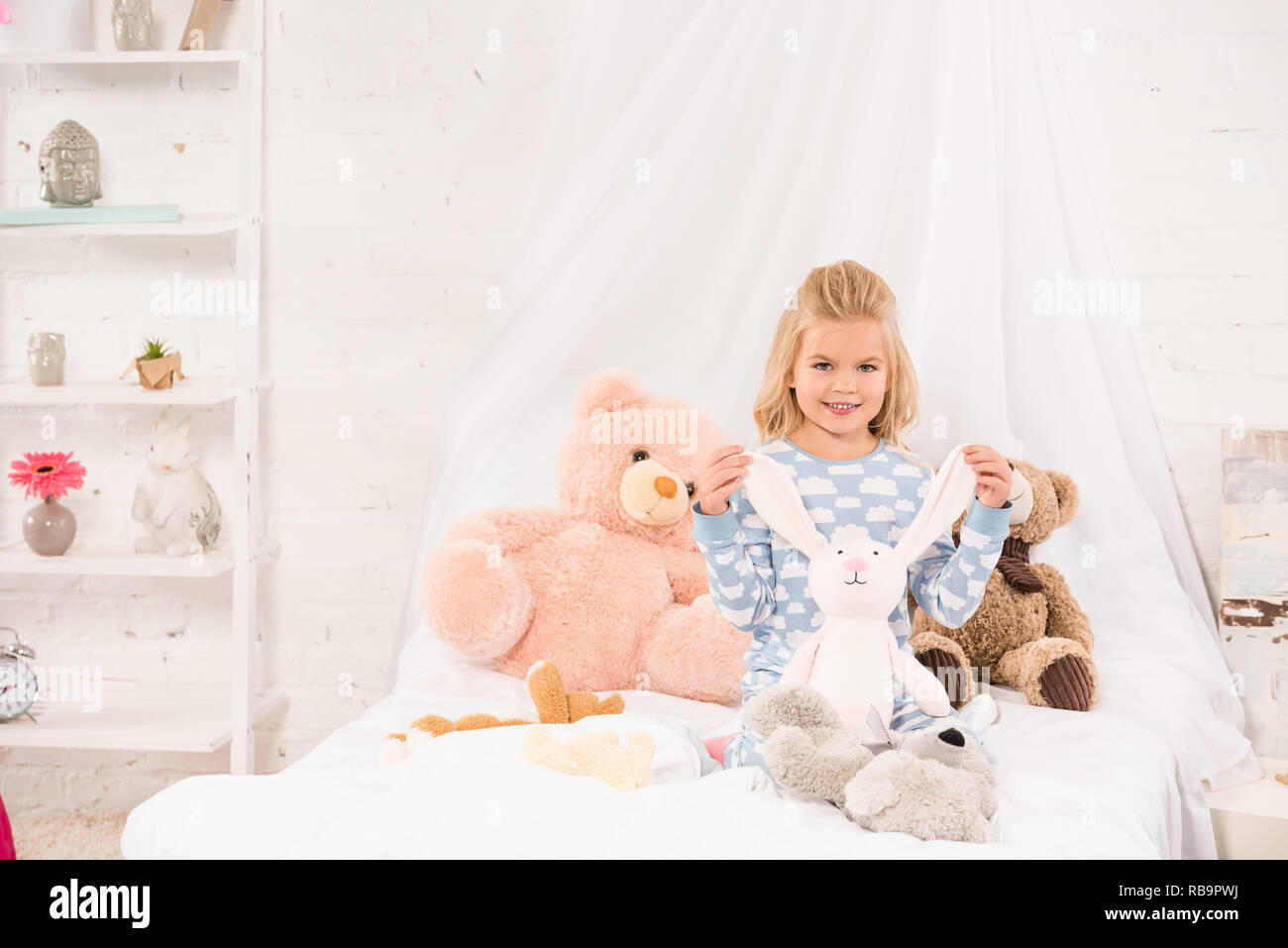 smiling cute child playing with soft toys in bed Stock Photo Alamy