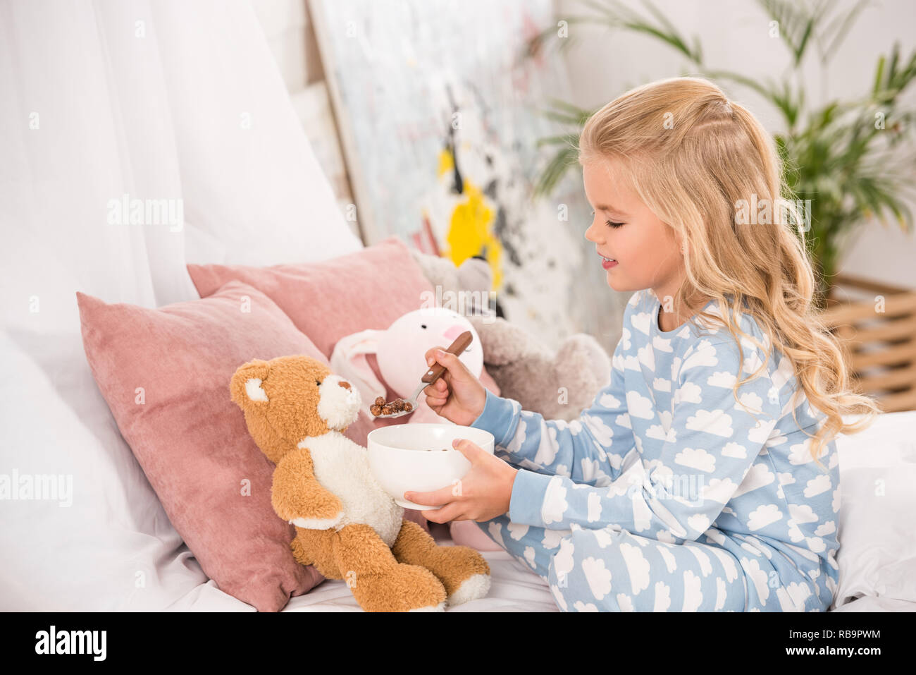 adorable child in pajamas feeding soft toys in bed Stock Photo Alamy