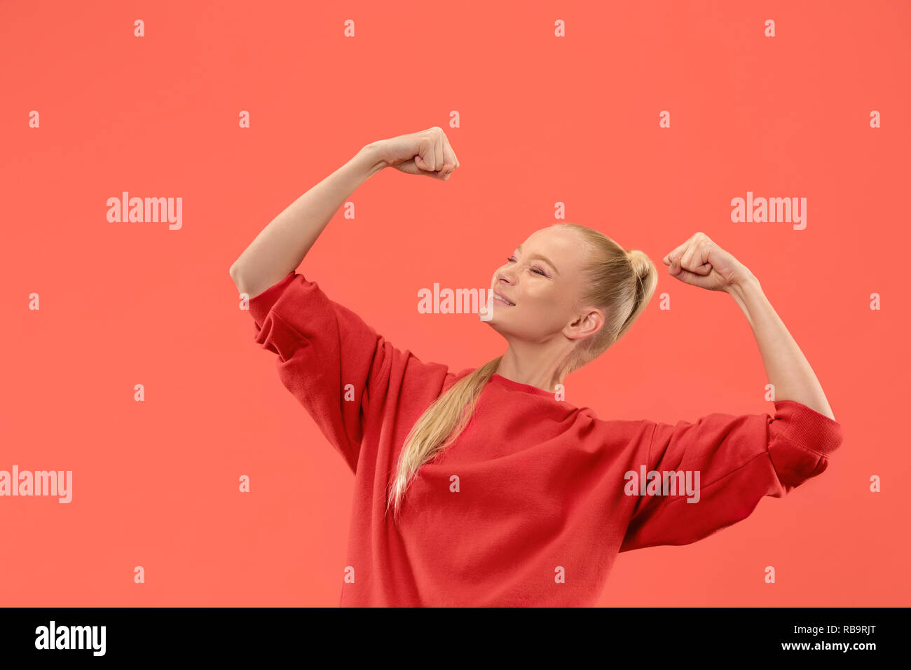 I won. Winning success happy woman celebrating being a winner. Dynamic image of caucasian female model on coral studio background. Victory, delight concept. Human facial emotions concept. Trendy colors Stock Photo