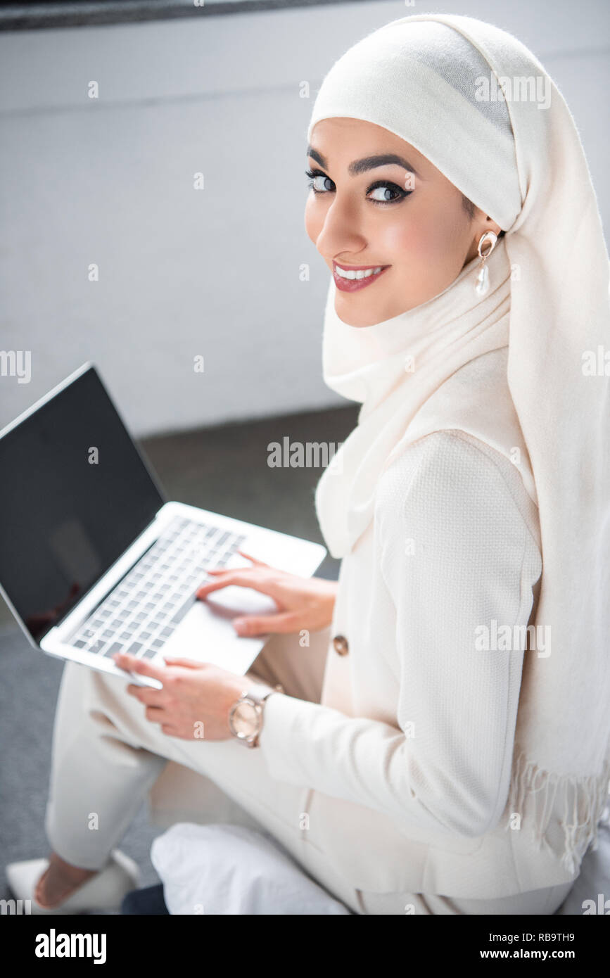 beautiful muslim woman using laptop with blank screen and smiling at ...