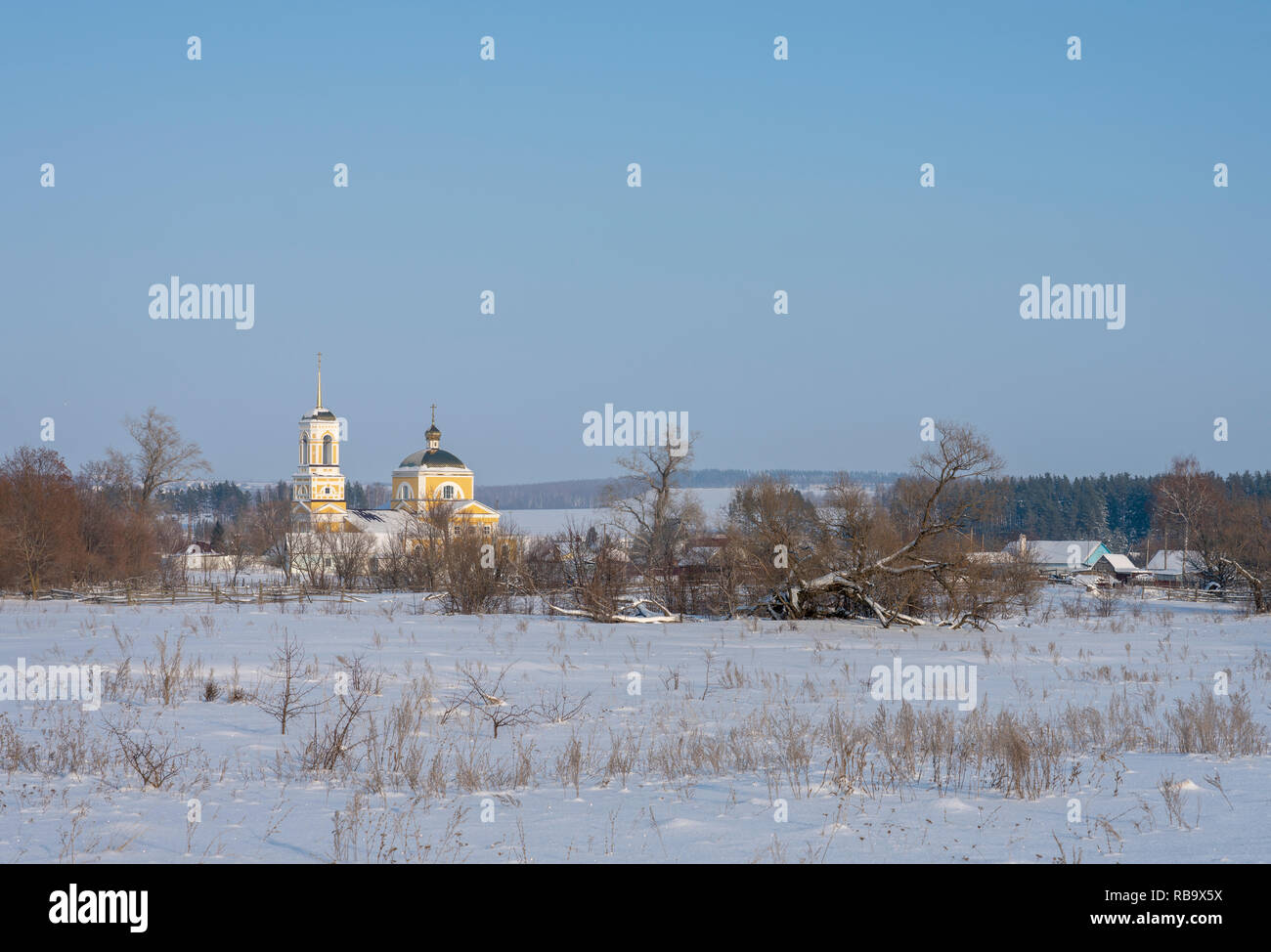 Winter village landscape with Church, the sun shines snow drifts. Stock Photo