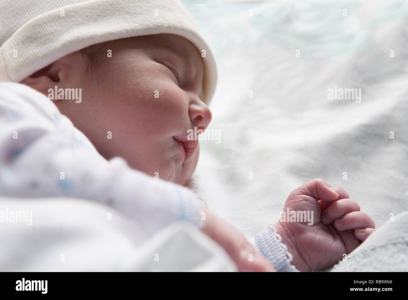 Newborn baby sleeping on side position. Few hours-old baby at hospital crib Stock Photo