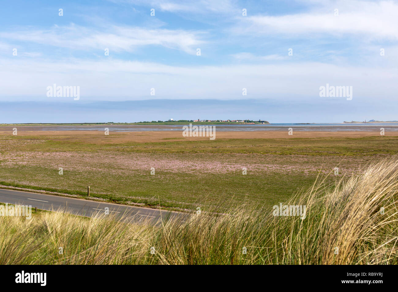 The Holy Island of Lindisfarne viewed from the tidal causeway road across the mud flats Stock Photo