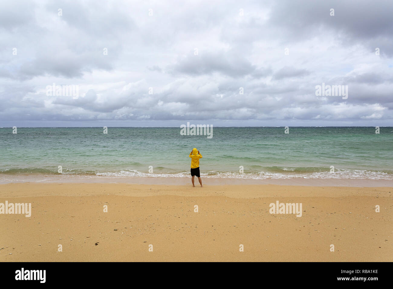 Young woman in yellow jacket standing, walking in shallow water on a ...