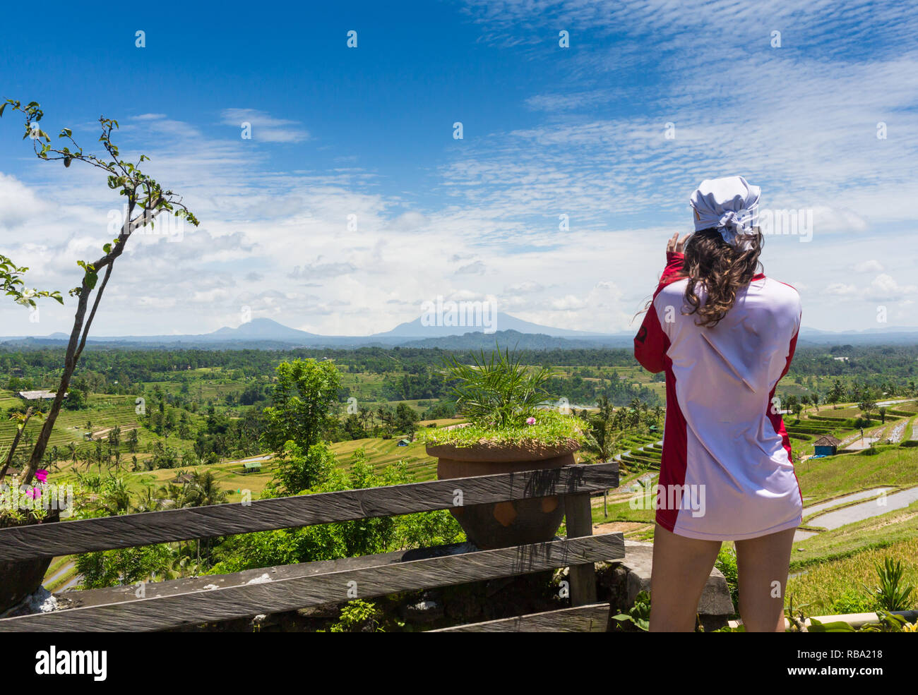 Family vacation lifestyle. Young woman stand on edge of overhanging bridge on high cliff. Happy girl looking at stunning tropical jungle view. Tukad Melangit is popular travel destination in Bali. Stock Photo