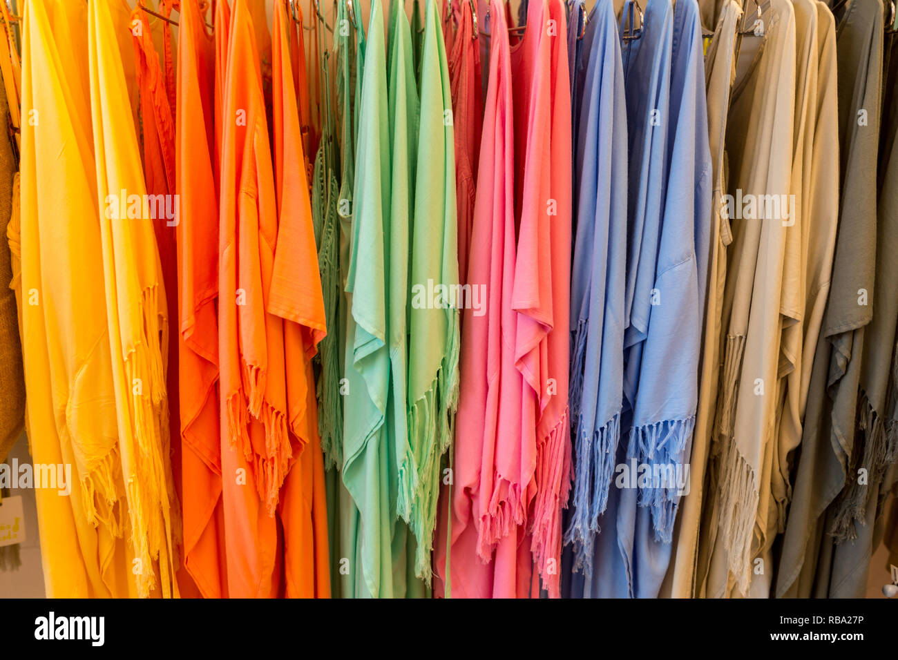 Fashion clothes on clothing rack - bright colorful closet. Close-up of rainbow color choice of trendy female wear on hangers in store closet or spring cleaning concept. Summer home wardrobe. Stock Photo