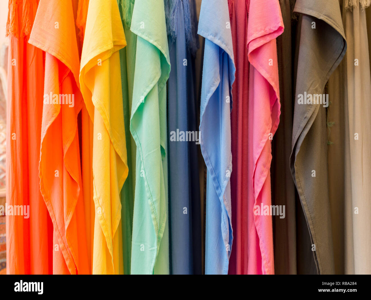 Fashion clothes on clothing rack - bright colorful closet. Close-up of rainbow color choice of trendy female wear on hangers in store closet or spring cleaning concept. Summer home wardrobe. Stock Photo