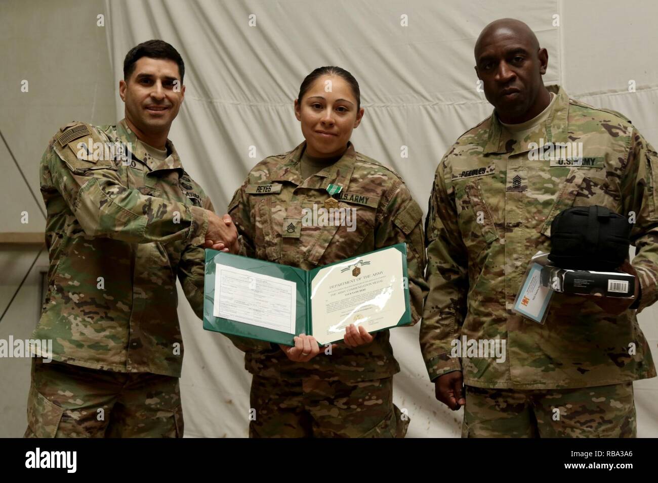 U.S. Army Staff Sgt. Miriam Reyes, a squad leader in Headquarters and Headquarters Company, 1st Battalion, 67th Armor Regiment, 3rd Armored Brigade Combat Team, 1st Armored Division, receives her award from the 1st Battalion, 77th Armor Regiment command team, Lt. Col. Johhny Casiano and Command Sgt. Maj. Maurice Peebles, after winning the Top Medic Competition at Camp Buehring, Kuwait, Dec. 19, 2016.  The stressful 36-hour competition, hosted by 3rd Armored Brigade Combat Team, 1st Armored Division, tested the Soldiers’ basic warrior skills, medical skills proficiency, and overall physical str Stock Photo