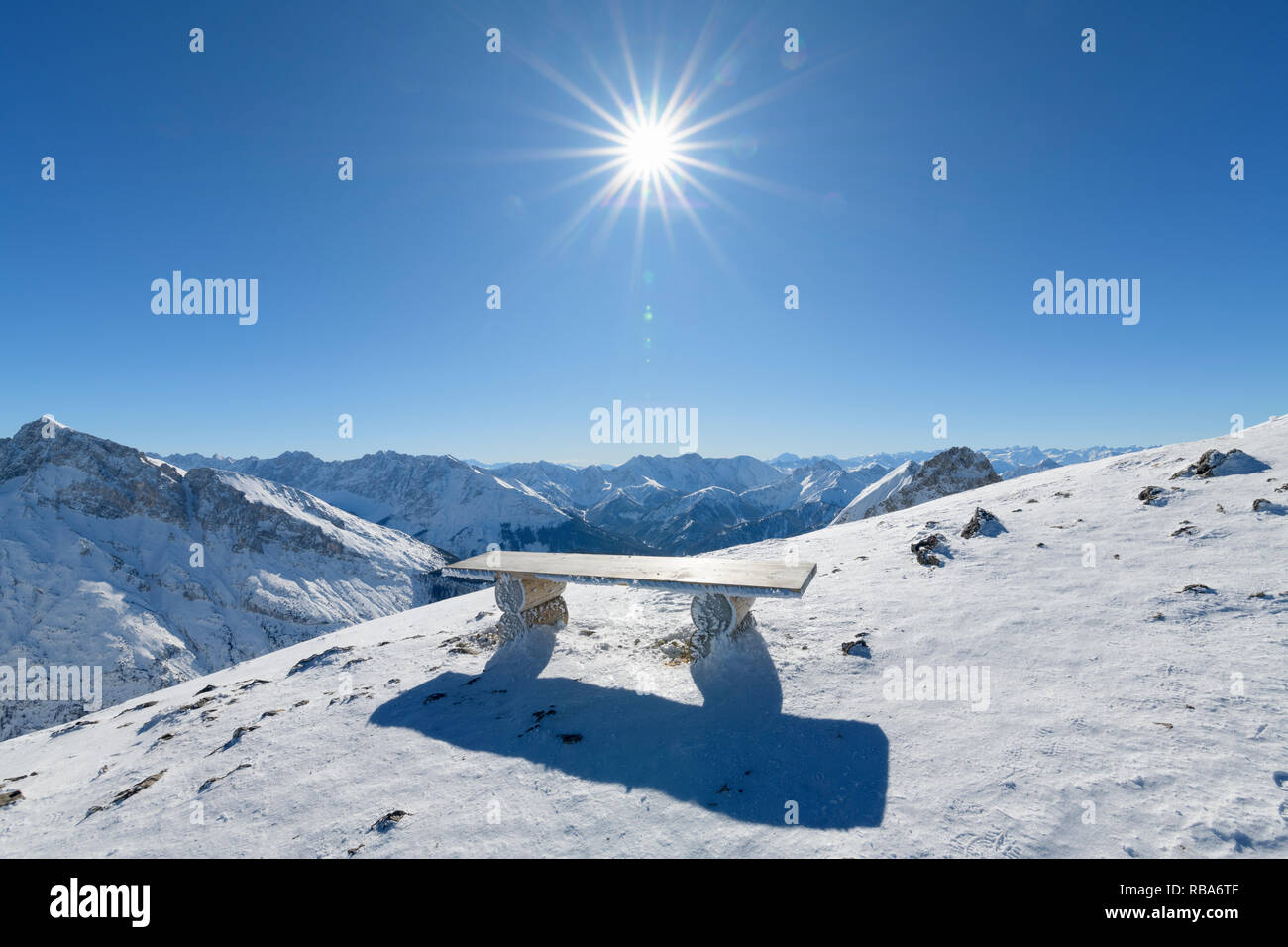 Bench on Karwendel mountainrange with sun in winter, Mittenwald, Upper Bavaria, Bavaria, Germany, European Alps Stock Photo
