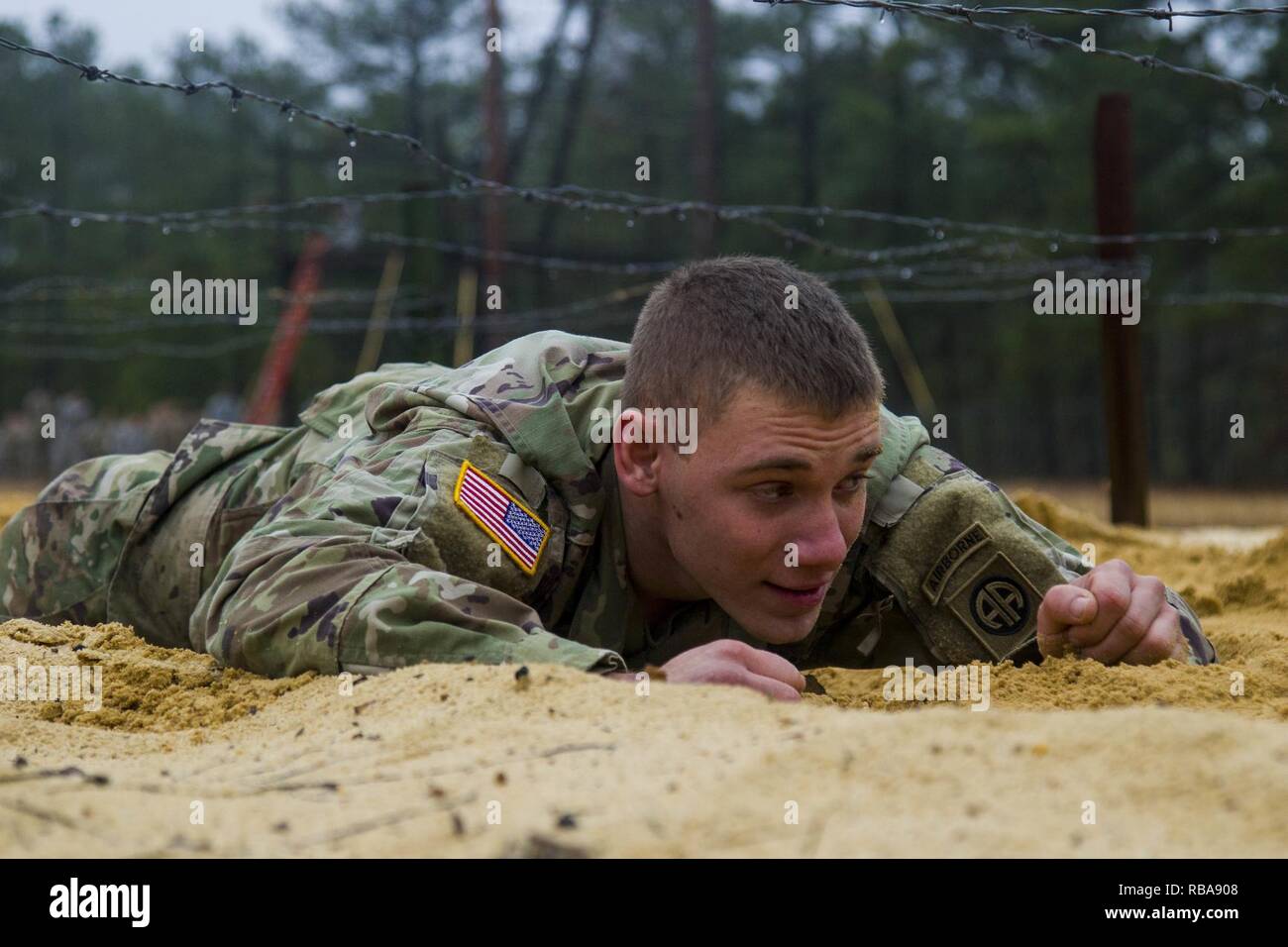 Pvt. Adam Klover, a rigger assigned to the 151st Division Aerial Delivery Company, 189th Combat Sustainment Support Battalion 'Superchargers,' moves through the damp sand for the low crawl obstacle as he tackles the air assault school obstacle course on Fort Bragg, N.C., January 4, 2017.  Air Assault teaches Paratroopers and Soldiers how to use rotary wing assets to accomplish the mission. Stock Photo