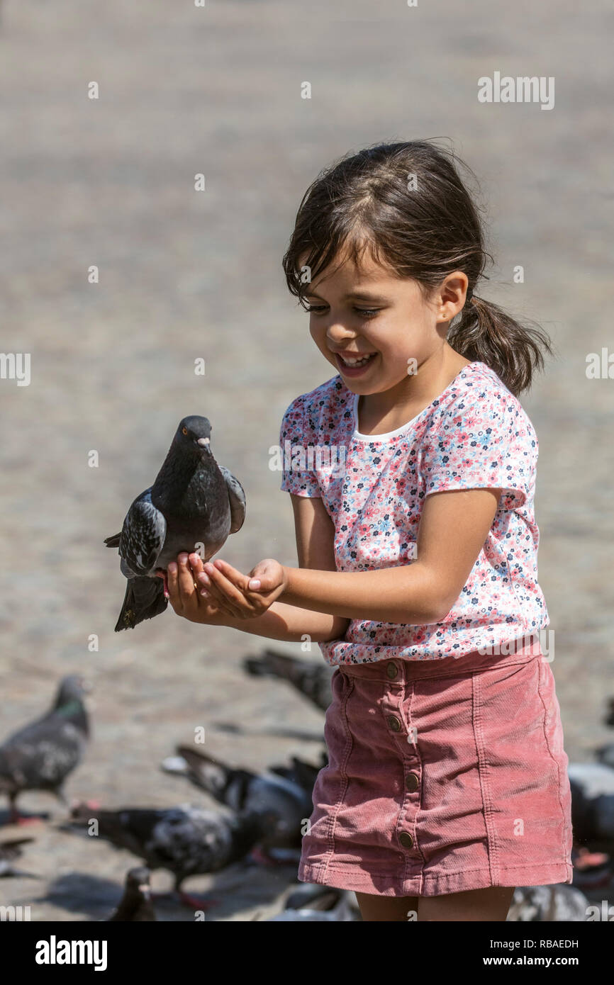 The Netherlands, Amsterdam, Dam Square. Child enjoys the presence of pigeons. Stock Photo