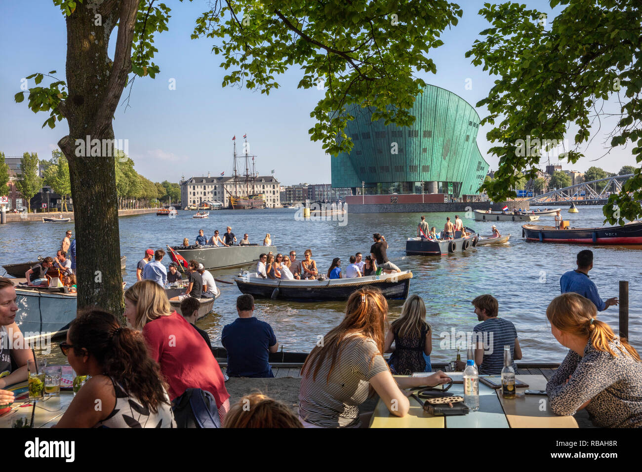 The Netherlands, Amsterdam. Outdoor terrace of restaurant Hannekes Boom near Central Station. Background National Maritime Museum and NEMO science Mus Stock Photo
