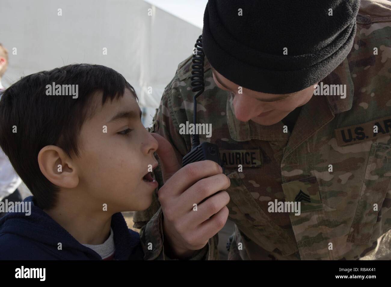 U.S. Army Sgt. Adam Fitzmaurice, assigned to the 396th Military Police Detachment, lets a child from a local orphanage speak on his radio during a holiday celebration at Mihail Kogalniceanu Airbase, Romania, Dec. 22, 2018. The base hosted the event to provide a memorable holiday season for children in the area and solidify the strong relationship the U.S. has with its Romanian ally. Stock Photo