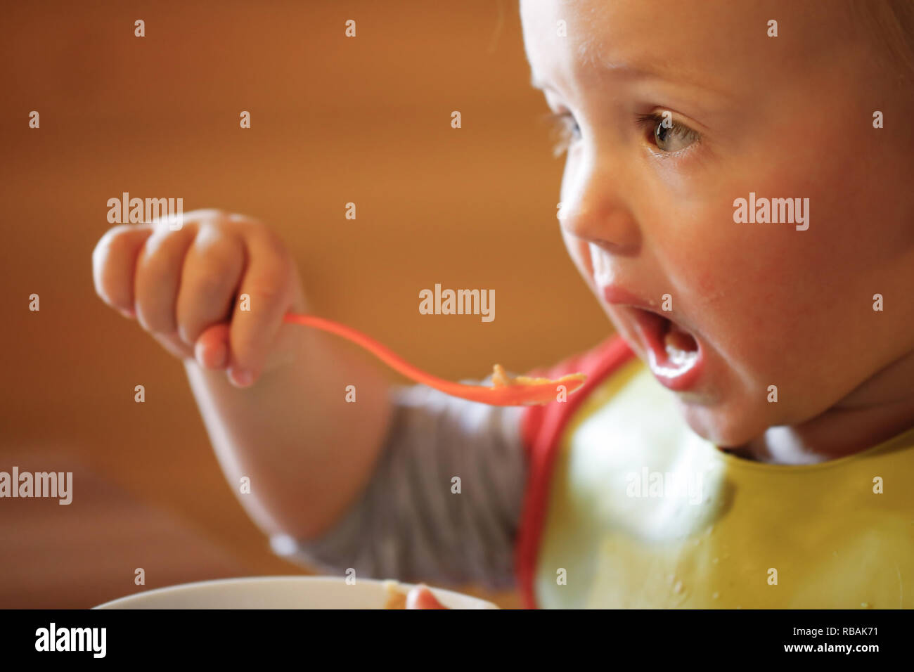 Child eating independently with a spoon, feeding himself, making a mess ...