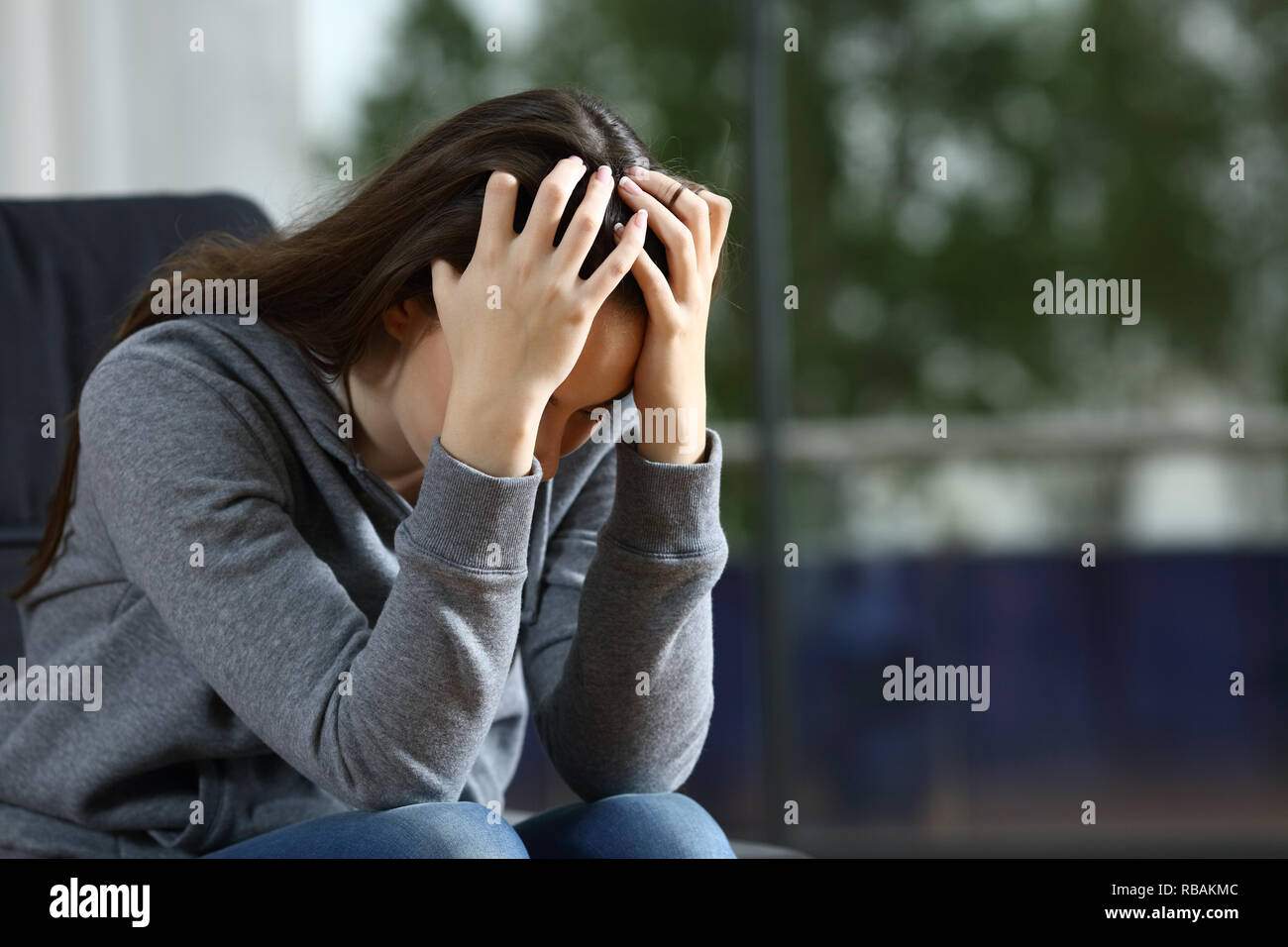 Sad woman complaining alone sitting on a couch at home Stock Photo