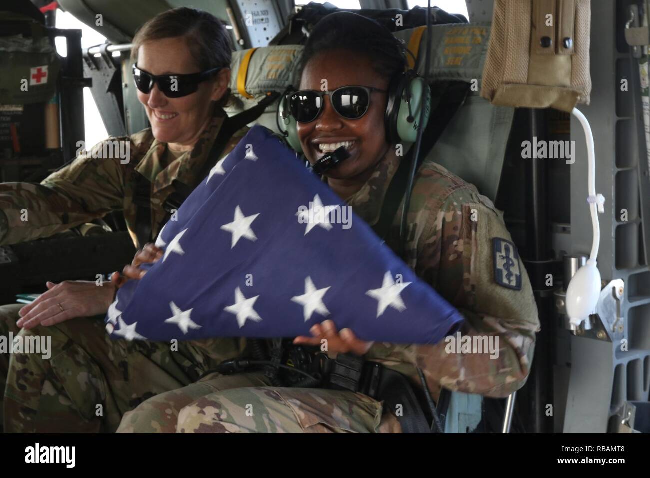 Sgt. Sylvia Mwangi, 452nd Combat Support Hospital, holds the American flag following an airborne reenlistment ceremony over Camp Arifjan, Kuwait, Dec. 28, 2018. Stock Photo