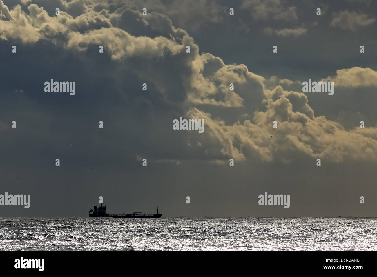 Commercial ship on the horizon of a glistening sea against an evening ...