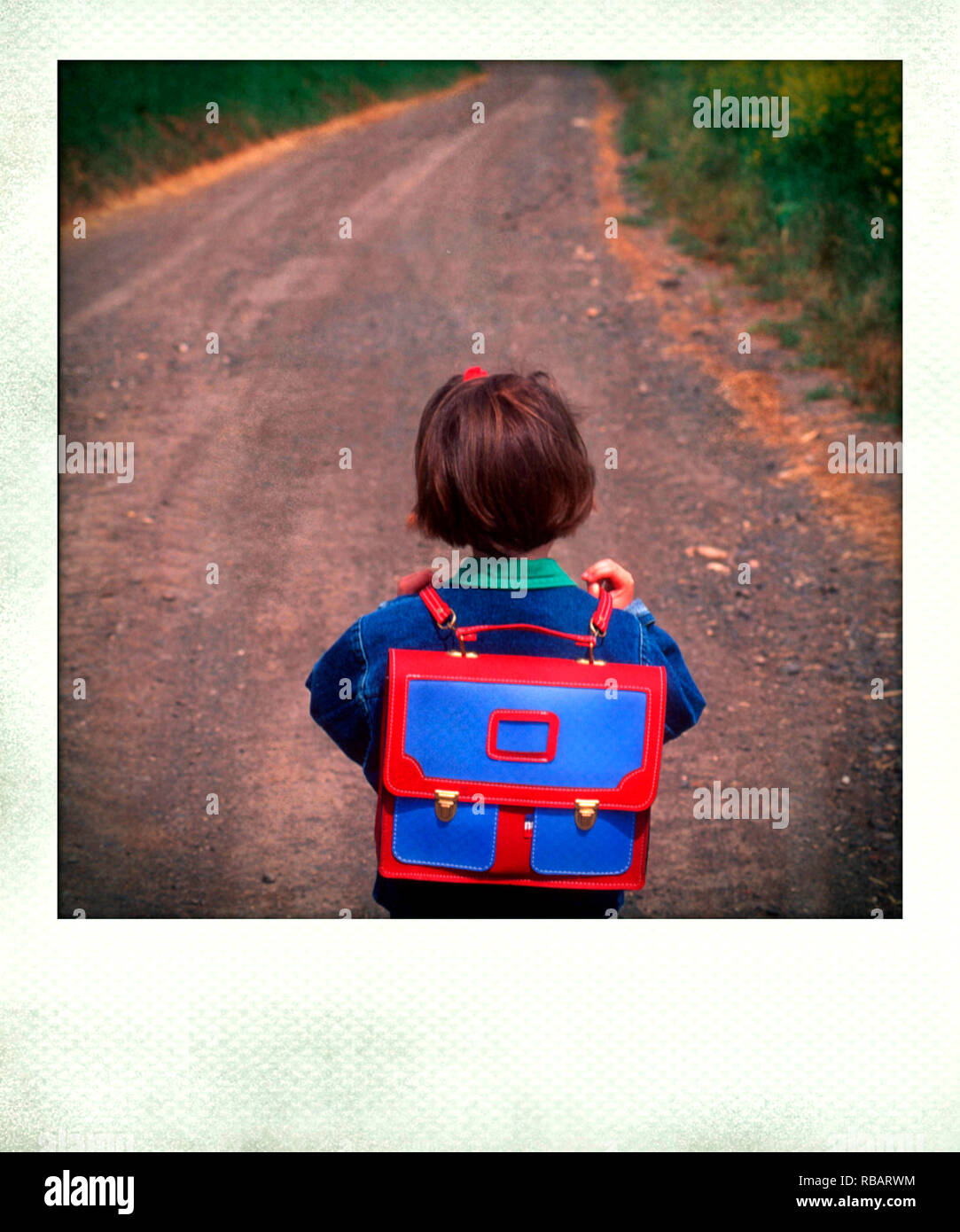 Polaroid photograph of a girl wearing a schoolbag on a rural road Stock Photo