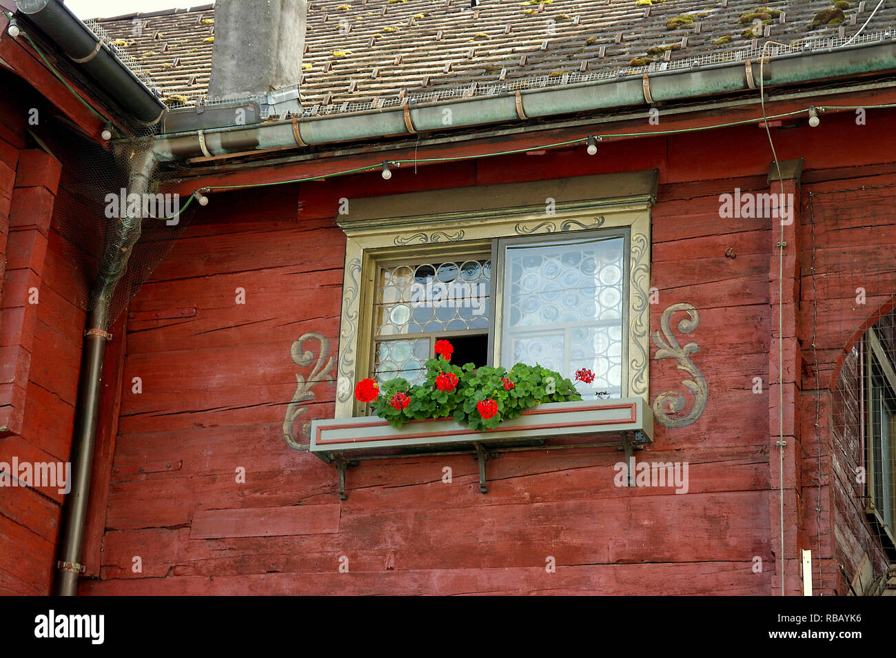 Austrian house window with ornate design and red geranium plants in window box Stock Photo