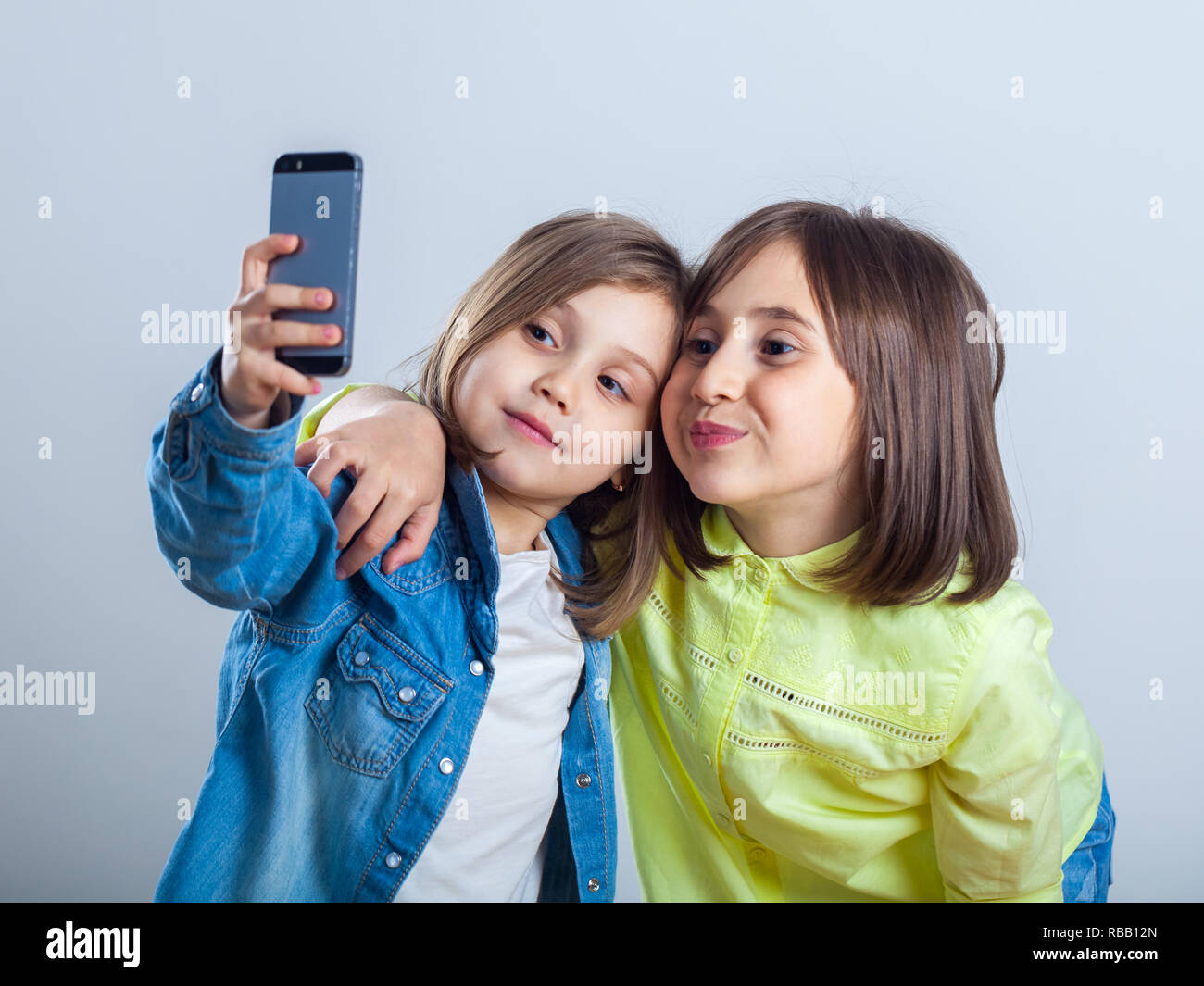 two sisters posing and taking selfies in the studio. Stock Photo