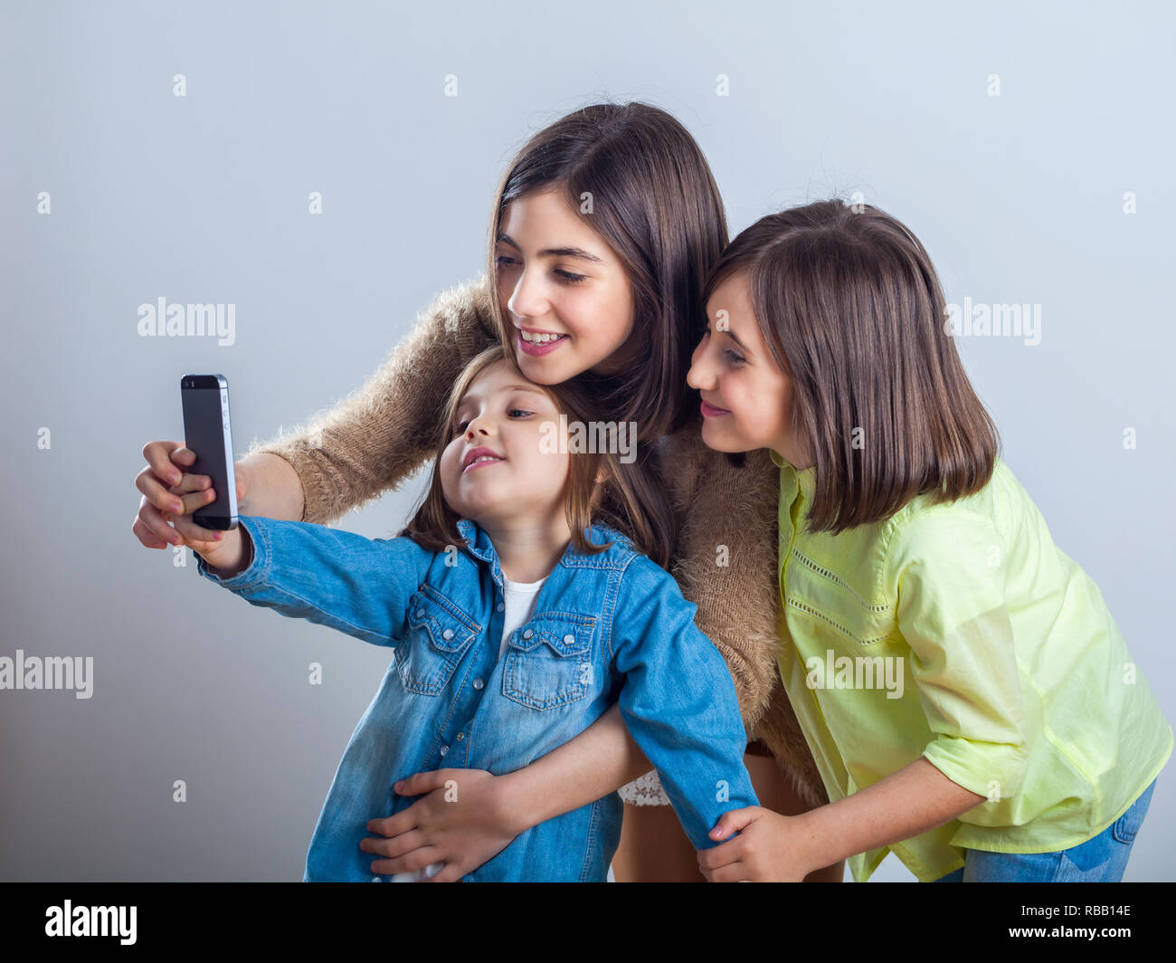 three sisters posing and taking selfies in the studio. Stock Photo