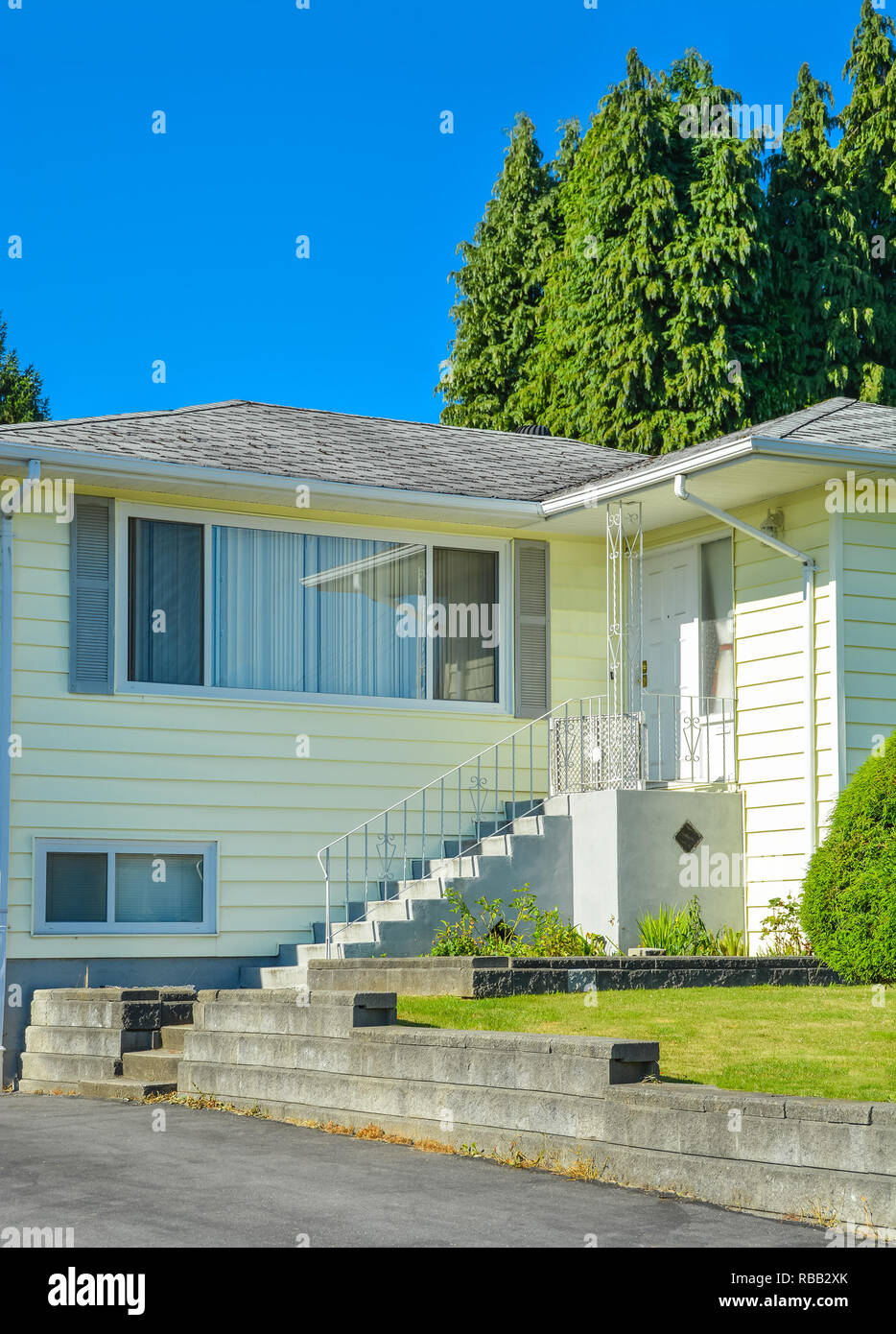 Entrance of family house with concrete doorsteps and asphalt driveway
