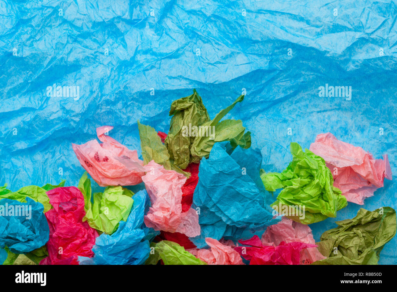 Crumpled colorful tissue paper on a blue tissue paper background Stock Photo
