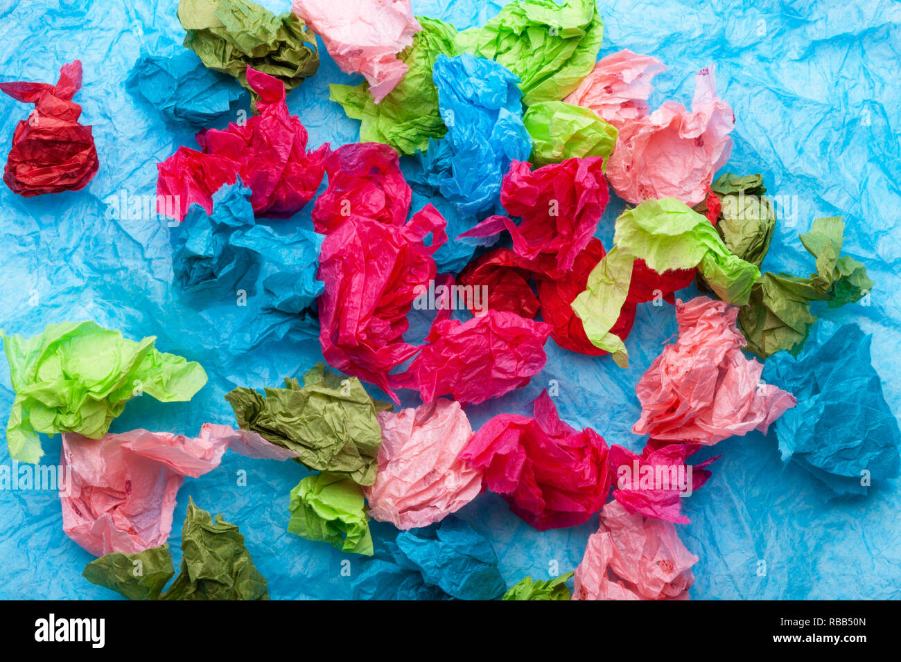 Crumpled colorful tissue paper on a blue tissue paper background Stock Photo