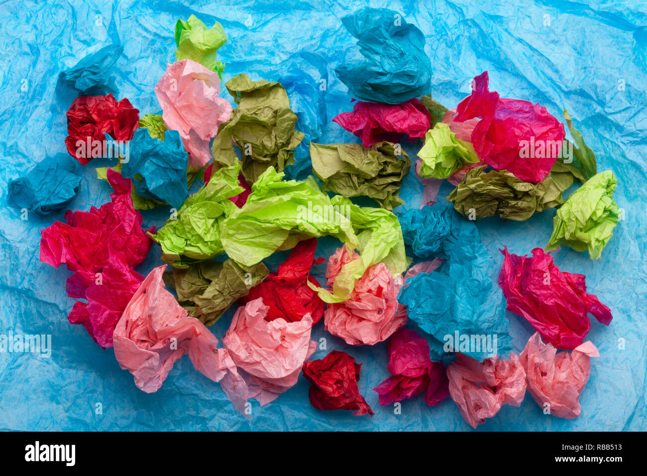 Crumpled colorful tissue paper on a blue tissue paper background